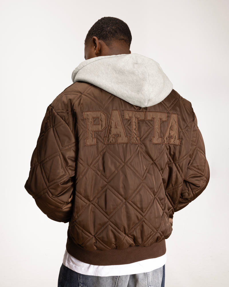 close up model shot of the back side of the leopard reversible bomber showing the patta branding and quilted paneling on the back.