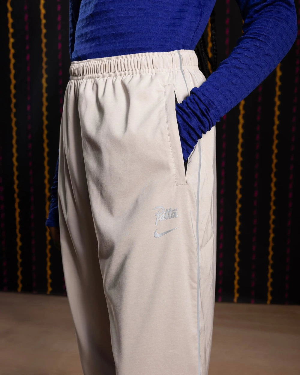 Nike x Patta Running Team track pants in sanddrift cream with reflective logos and side pocket detail.