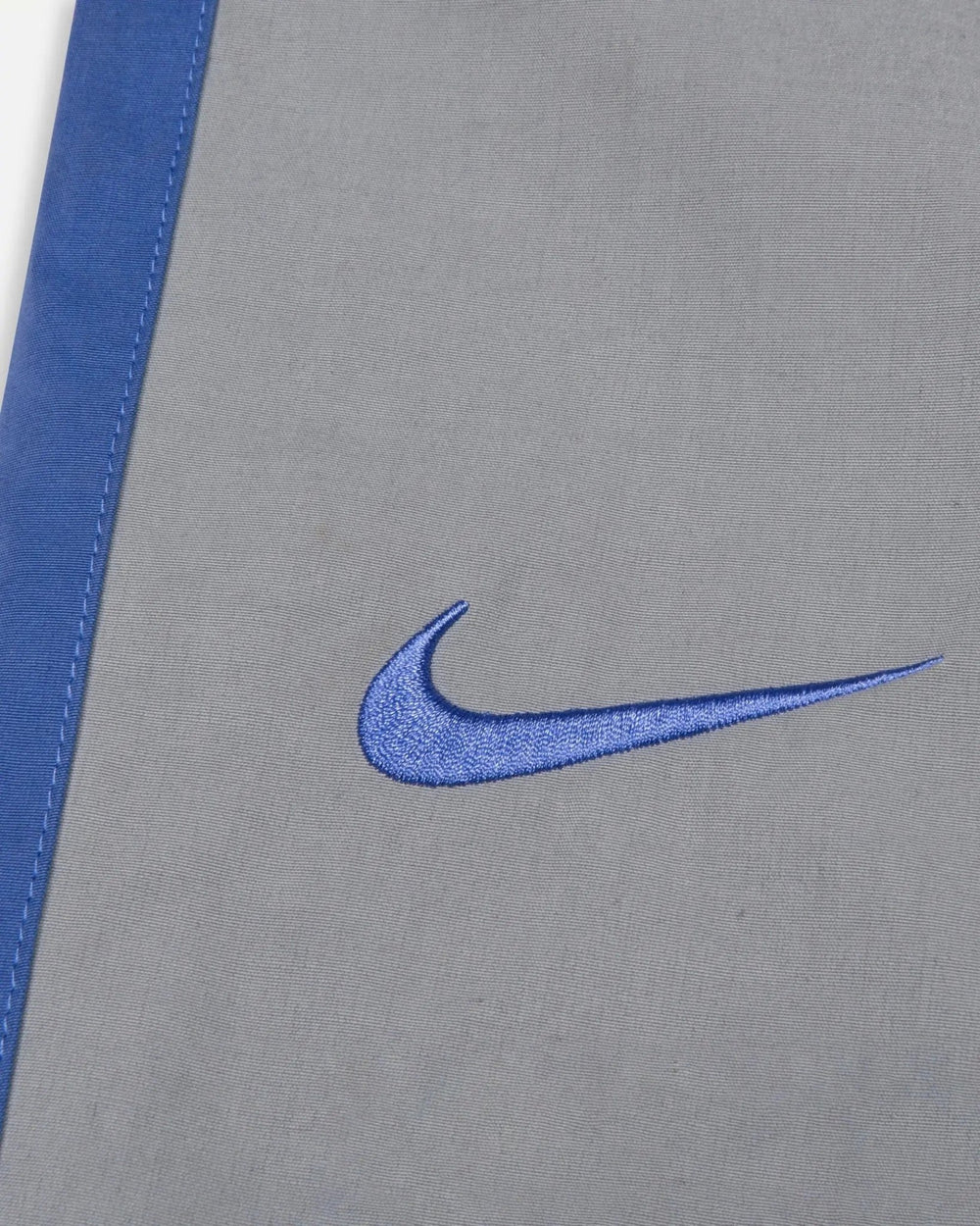 Embroidered sapphire blue Nike swoosh detail on the particle grey Patta x Nike NRG Track Pant.